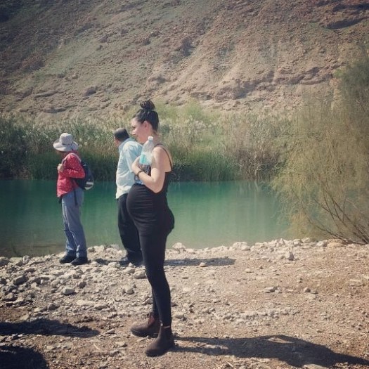 אישה בהריון עומדת ליד אגם- שמורת הטבע עיינות צוקים