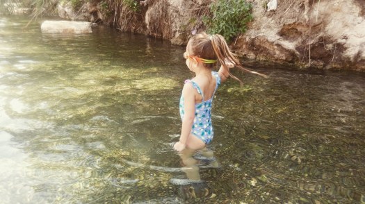 ילדה נהנית וזורקת אבן בתוך בריכת מים רדודים- הסחנה- גן לאומי גן השלושה