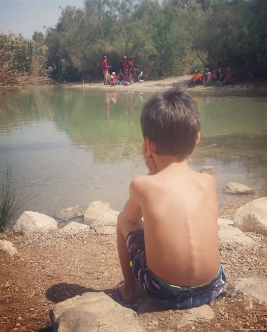 ילד יושב עם גבו למצלמה ומסתכל על מי האגם- עין פשחה