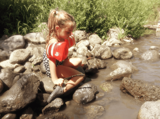 ילדה משחקת לצד הנחל